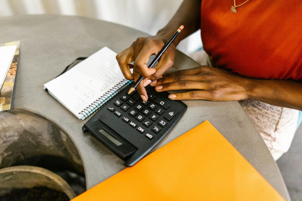 An African American woman using a calculator and notepad for budgeting.